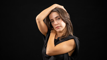 A chest-up headshot of a young, brown-haired woman taken in a studio setting with a black background
