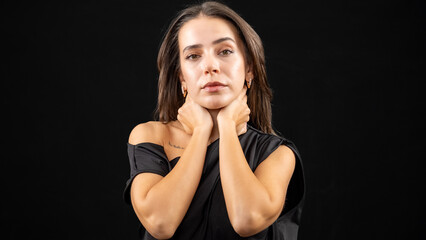 A chest-up headshot of a young, brown-haired woman taken in a studio setting with a black background