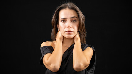 A chest-up headshot of a young, brown-haired woman taken in a studio setting with a black background