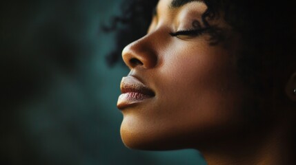 Fototapeta premium Close-up portrait of a serene woman with curly hair, eyes closed, against a blurred background