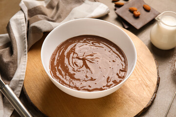 Bowl with delicious hot chocolate, napkin and jar of milk on brown background. Closeup