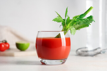 Glass of bloody mary with celery on light background