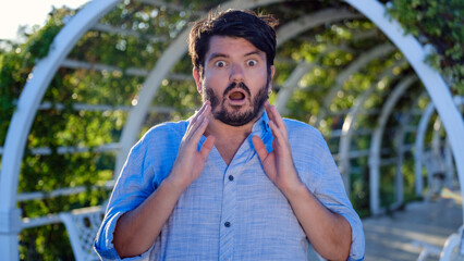 A middle-aged, dark-haired businessman wearing a shirt is looking at the camera in a sunny,...