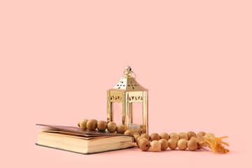Koran with prayer beads and fanoos on pink background. Ramadan celebration