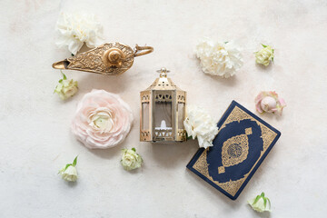 Fanoos with Koran and beautiful flowers on white grunge background. Ramadan celebration