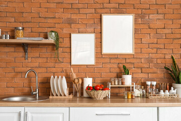 Different spices with vegetables, utensils and plants on counters in kitchen