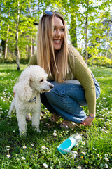 Cute young woman with her poodle dog in the park at springtime