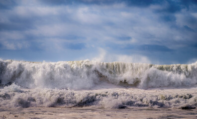 Huge waves begin to break, forming a mix of wash and water during a Winter storm onset along the coastline of Southern California