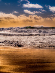 Portrait style photograph of Southern California Beach during a dramatic weather Winter storm pattern causing dangerous surf and dramatic sky in Manhattan Beach