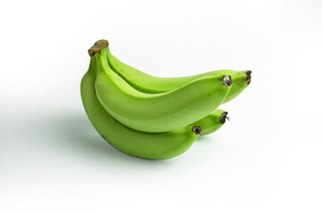 A bunch of green bananas are stacked against a white background, showing a close-up view of the unripe fruit
