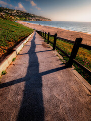 Redondo Beach walking ramp leading down to the beach on a beautiful day with blue sky, few scattered clouds with an empty beach and a clear view of the Palos Verdes Peninsula