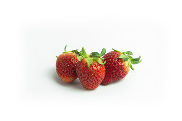strawberries are arranged in a heart shape on a white background. The berries are red with green stems, some showing a transition to lighter, unripe areas. The image is a top-down view