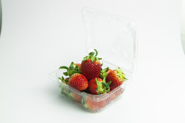 strawberries are arranged in a heart shape on a white background. The berries are red with green stems, some showing a transition to lighter, unripe areas. The image is a top-down view