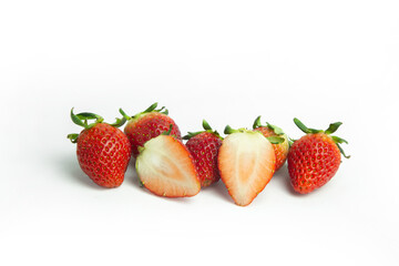 strawberries are arranged in a heart shape on a white background. The berries are red with green stems, some showing a transition to lighter, unripe areas. The image is a top-down view