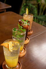 Close-up of refreshing drinks on a rustic wooden table, highlighting the vibrant colors and garnishes.