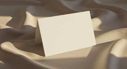 Blank card on draped fabric, soft light and shadows, elegant scene.
