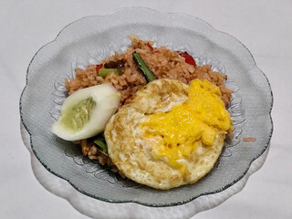 Fried rice, vegetables, crackers with fried egg as a side dish. Fried rice on a glass plate.