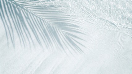 Palm leaf shadow on abstract white sand beach background. Sunlight on water surface, a beautiful abstract background concept banner for summer vacation at the beach. Top view of tropical leaf shadow