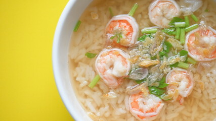 rice soup with shrimp in white bowl on yellow background