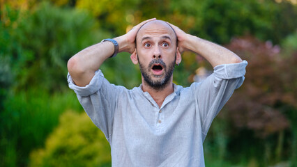 A middle-aged handsome businessman looking at the camera with a surprised expression in a...