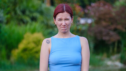A young and beautiful businesswoman on a summer day in a wooded park, looking at the camera while...