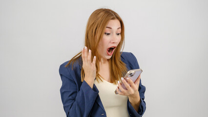Naklejka premium A young businesswoman in a suit is having a good time with her cellphone in a studio setting with a white background