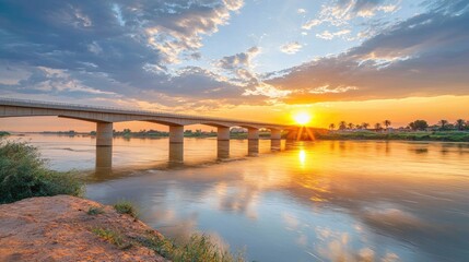 Serene Sunset Over Tranquil River with Bridge Reflection and Clouds