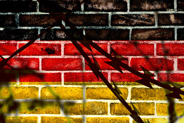 A wall and flag of Germany behind the barbed wire