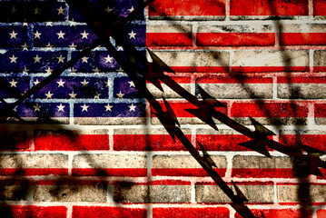 A wall and flag of the United States of America behind the barbed wire