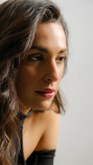 Naklejka premium In a studio setting with a white background, a young black-haired woman wearing a black blouse and jeans strikes an artistic pose