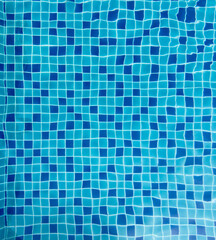 Colorful tile patterns of a swimming pool under sunlight creating shimmering reflections on water surface