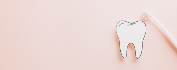 World Dentist Day flat lay, paper tooth and toothbrush on pastel pink.