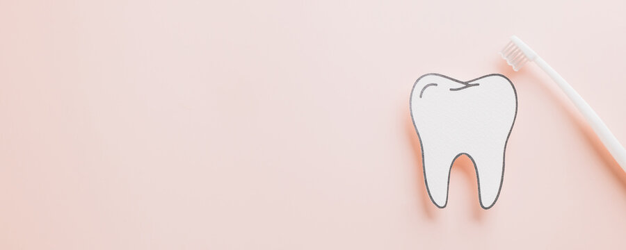 World Dentist Day flat lay, paper tooth and toothbrush on pastel pink.
