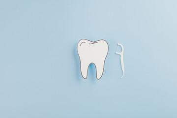 Dentist Day concept. A paper tooth model and floss on a blue background