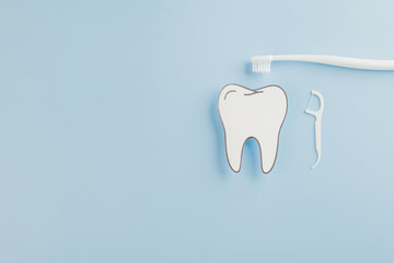 Dentist Day focus. A blue background featuring a paper tooth model, floss, and toothbrush