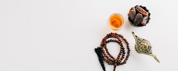 Overhead view of dates in a bowl, prayer beads, tea, and teapot for Ramadan.
