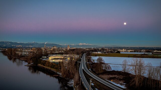 Delta BC Canada - February 11th 2025: Sunset at Deas Island Regional Park waterfront with mountain and moonrise