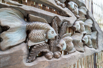 Intricate Wooden Carving of Fish with Natural Elements and Details