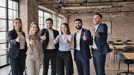Team Success: Diverse team members are standing in office, holding a thumbs up, show the team is a happy team, achieving goals.