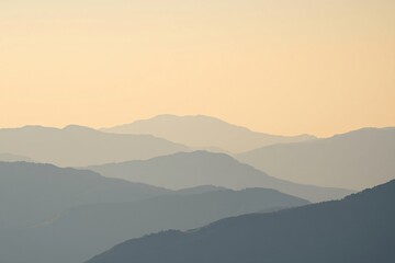 Obraz premium serene sunrise landscape with layers of misty mountains