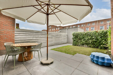 An inviting outdoor patio showcases a round table with stylish chairs, a large umbrella, and a...