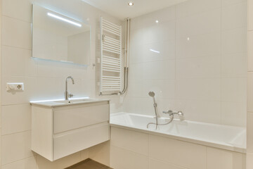 A sleek and contemporary bathroom featuring a bathtub, wall-mounted mirror, and stylish fixtures, highlighting minimalist aesthetics and functionality.