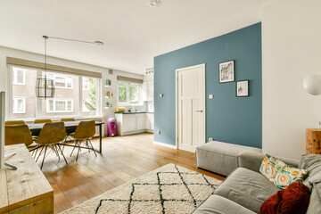 A stylish living room featuring a blue accent wall, comfortable seating, and ample natural light,...