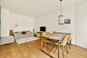 A contemporary living space showcasing a cozy dining area and sleek furniture, featuring wooden floors and neutral colors for a chic ambiance.