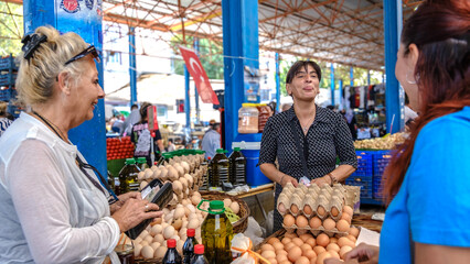 A young woman and her mother happily shopping at a fruit and vegetable bazaar on a summer day