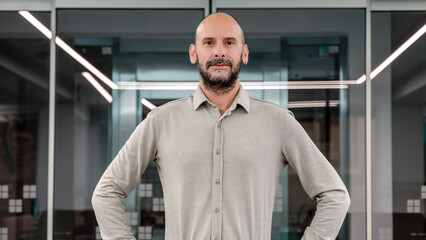 A middle-aged light-skinned businessman smiling while looking at the camera in an empty office...