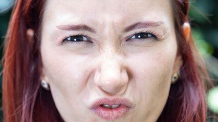 A very close-up headshot of a young woman making funny facial expressions while looking at the camera