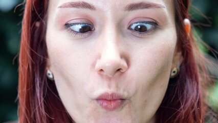 A very close-up headshot of a young woman making funny facial expressions while looking at the camera