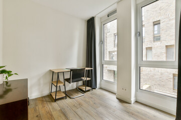 A sleek modern interior featuring a minimalist design, large windows providing ample natural light, and simple furniture elements that create a cozy atmosphere.