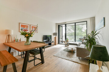 A bright and modern living space featuring a cozy seating area, elegant decor, and large windows that invite natural light and greenery indoors.